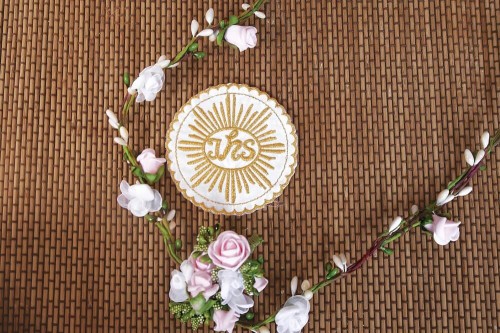 Haftowany emblemat z symbolem IHS w formie hostii.