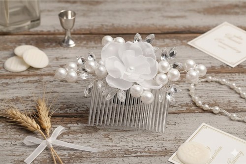 Delikatny biały kwiat otoczony perłami i kryształowymi detalami.